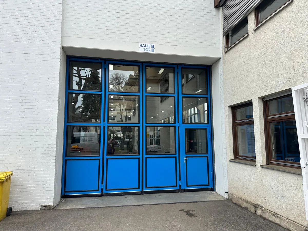 Industrietor mit Faltschiebetoren und Glaseinsatz an einer Halle
